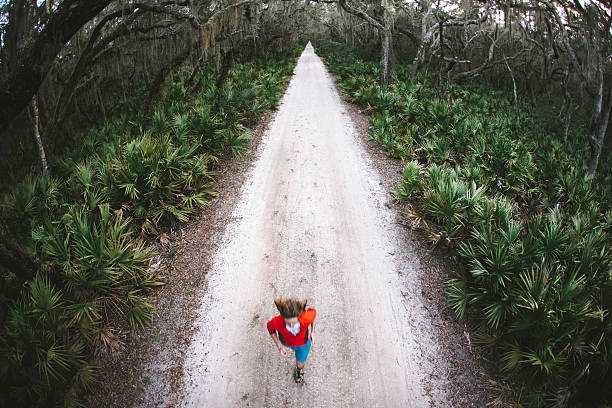 istock Solitary male runs under trees on road at sunset 167313249