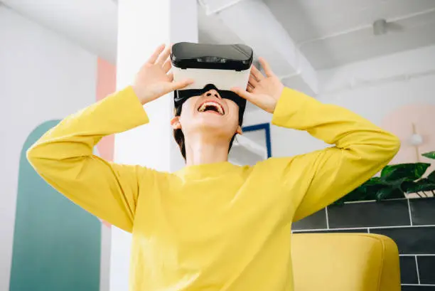 Photo of Young Asian woman wearing virtual reality glasses for looking entertainment and virtual game.