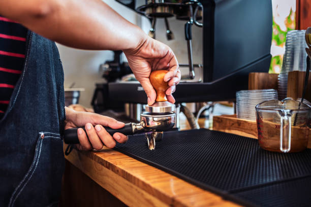 istock Hand of Barista cafe making coffee with manual presses ground coffee using a tamper making an espresso coffee on the wooden counter bar at the coffee shop 1673186484
