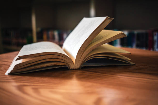 istock Vintage style.An open book or textbook vintage style in the library with light from the window on the reading table and the corridor of the bookshelves in the school classroom background.Education learning concept 1673186629