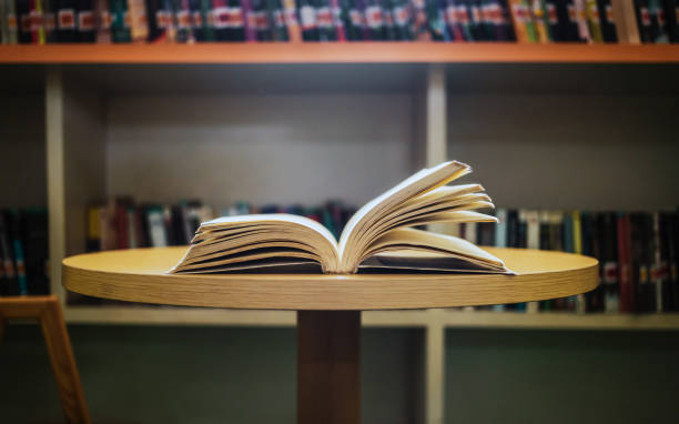 istock Vintage style.An open book or textbook vintage style in the library with light from the window on the reading table and the corridor of the bookshelves in the school classroom background.Education learning concept 1673186635
