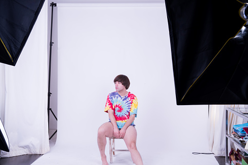 A gender fluid, non-binary freelance model with a brown hair does a studio photoshoot in an at-home studio in Thailand.