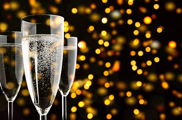 tre bicchieri di champagne con sparklings, giallo luci in background - champagne flute jubilee champagne wine foto e immagini stock