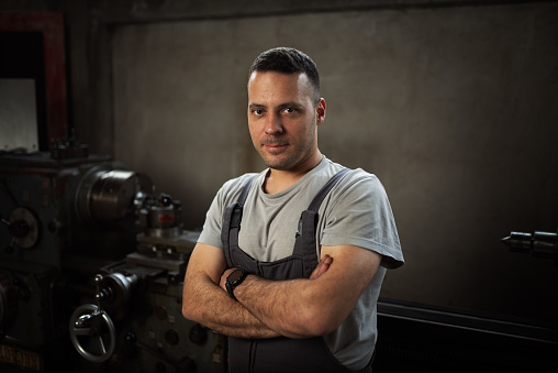 Hero shot of a metalworking man in the metalworking shop infront of a turning machine
