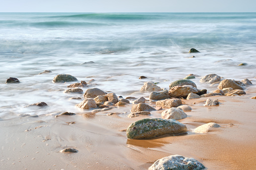 Beach panorama with pebbles on the shore on a sunny day - Long exposure