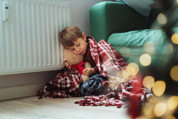 istock cute little boy wrapped id plaid sitting by heater 1673312109