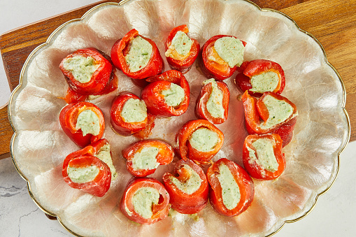 Red bell pepper stuffed with avocado filling on plate.