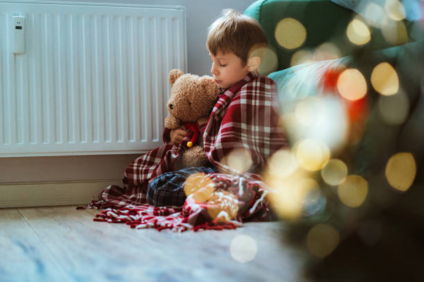 istock cute little boy wrapped id plaid sitting by heater 1673314199