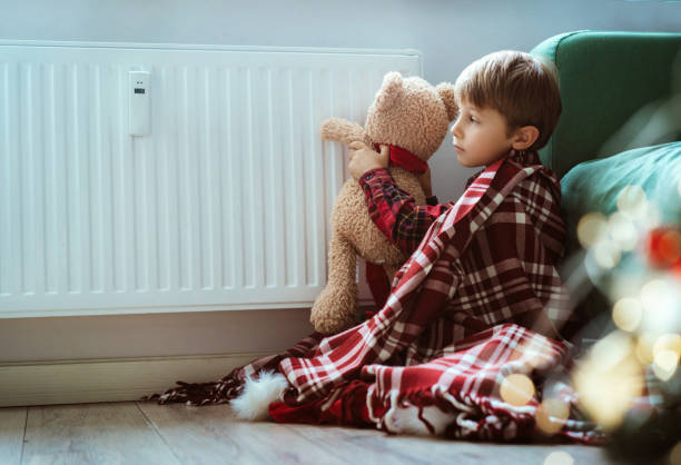 istock cute little boy wrapped id plaid sitting by heater warming teddy bear paws 1673314716