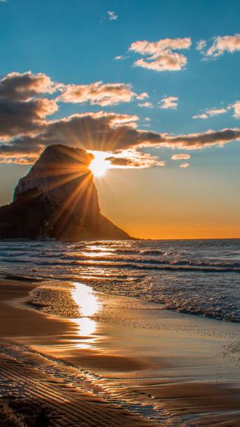istock Vertical of sunlight beaming behind a cliff in sea waves 1673317829