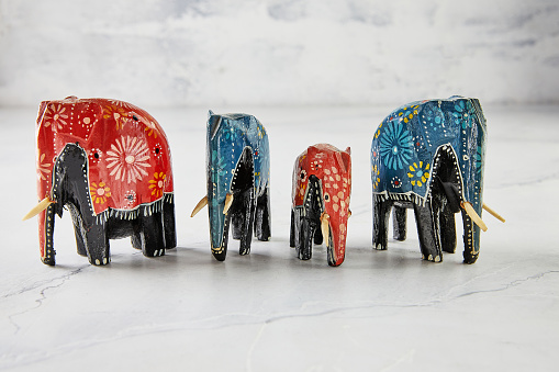 Elephant figurines of different colors and shapes on white marble.