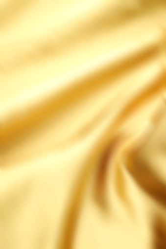 Close-up of defocused crumpled gold satin texture background.