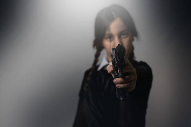 istock A girl with braids in a gothic style on a dark background with weapons 1673328624
