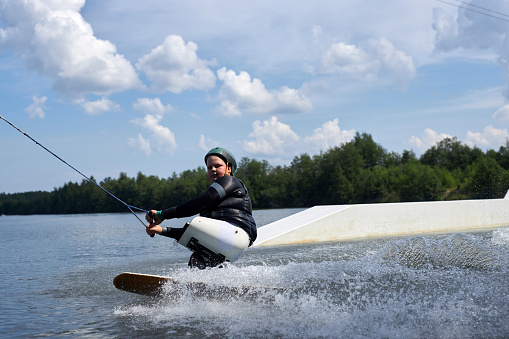 Action portrait of sportsman with disability enjoying fast speed wakeboarding on water with adaptive equipment, copy space