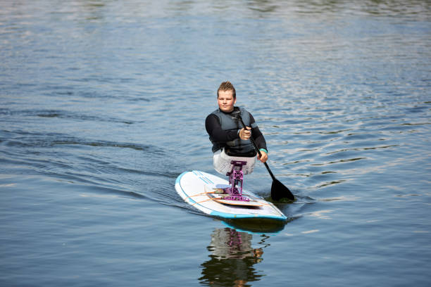 istock Boy with disability paddle boarding on water with adaptive sports equipment 1673350322