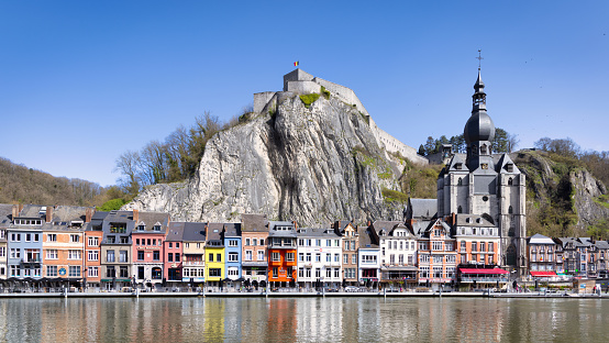 Dinant Cityscape at the waterfront of River Meuse under blue summer sky.  Famous Notre Dame de Dinant Collegial church - Collégiale Notre Dame de Dinant - Church of Our Lady from the 13th-century, old gothic cathedral and huge chalk cliff behind the Town of Dinant. 102 MPixel Hasselblad X2D Cityscape. Dinant, Wallonia, Namur, Belgium, Europe.