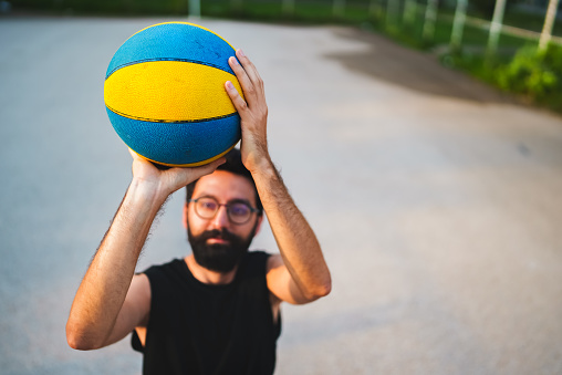 Young man playing basketball in the street.