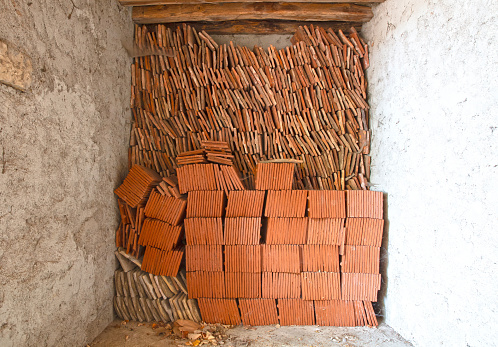 Stack of terracotta roof tiles in an old garage, France