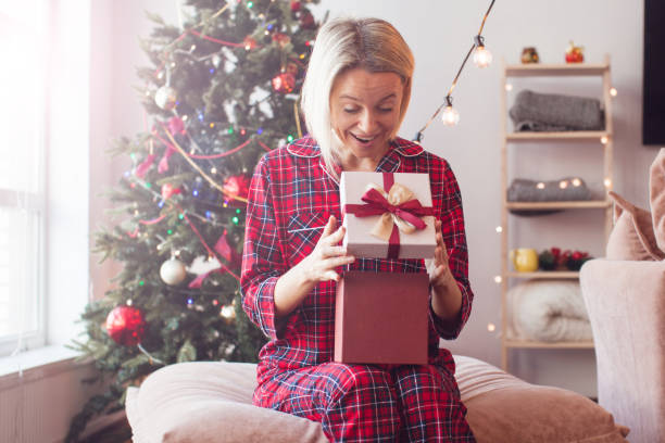 istock Middle aged Woman opening her present on Christmas 1673441415