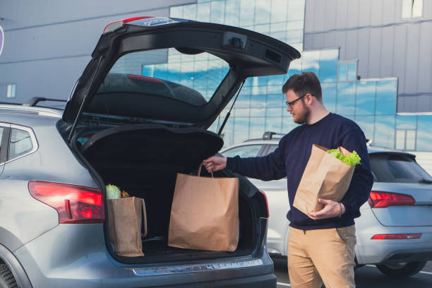 istock happy man put groceries bag in car trunk 1673446739