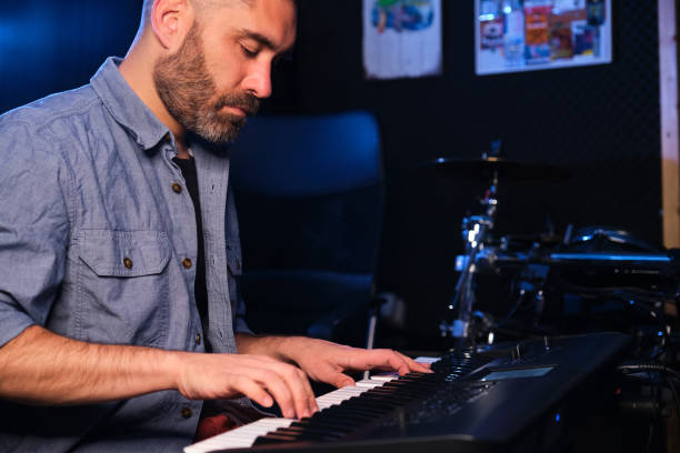 istock Musician man playing keyboard synthesizer piano in a recording studio. 1673456498