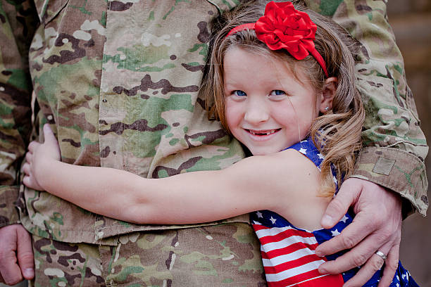 A smiling young girl hugging her soldier father stock photo