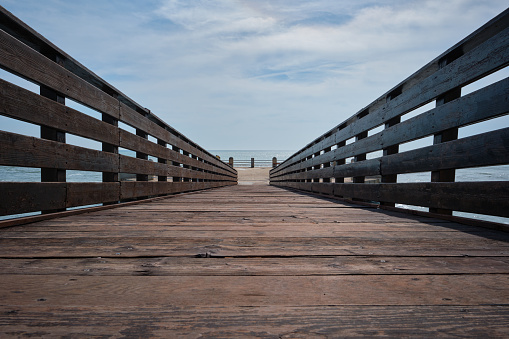 Wooden bridge over the sea, at the bottom the horizon over the ocean