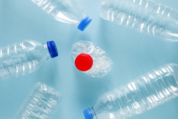 istock Crushed plastic water bottles with blue caps standing around crushed plastic water bottle with red cap on blue background 1673491736