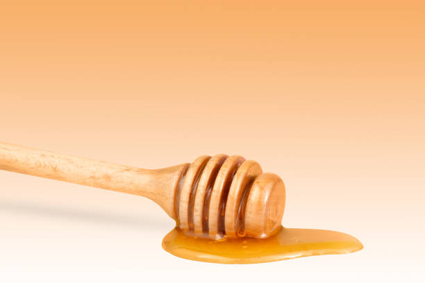 istock Honey on a wooden stick on orange background. 1673499290