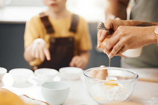 Hands, crack egg and cooking in kitchen on bowl on table with family in home. Food, bakery and break eggshell for ingredient in flour for healthy diet, protein nutrition and preparation of pastry.