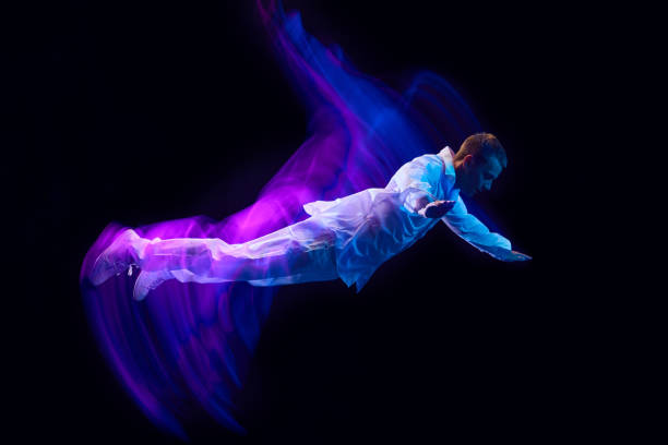 istock Freedom. Young guy in stylish clothes falling down against black studio background in neon with mixed lights effect. Levitation 1673540858