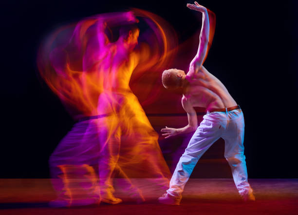 istock Inspiration and freedom. Young shirtless guy making chaotic movements against black studio background in neon with mixed lights effect 1673540887