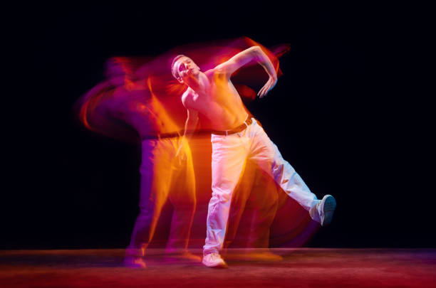 istock Inspiration and freedom. Young shirtless guy making chaotic movements against black studio background in neon with mixed lights effect 1673540889