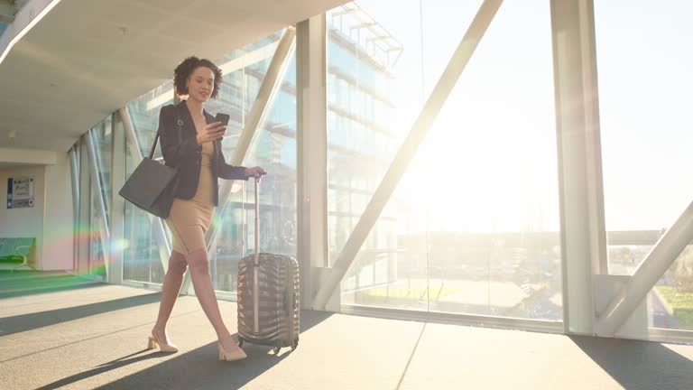 Phone, airport and walking business woman travel with a flight in a terminal for corporate convention. Luggage, professional and entrepreneur texting on conference trip for global tour or journey