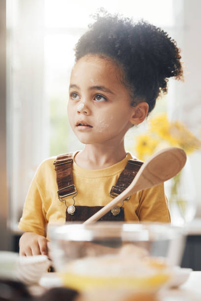 istock Kid in kitchen, baking with wooden spoon and cake flour on face, little baker making breakfast or cookies. Learning, cooking and boy chef in home with mixing bowl, tools and food, child in morning. 1673542450
