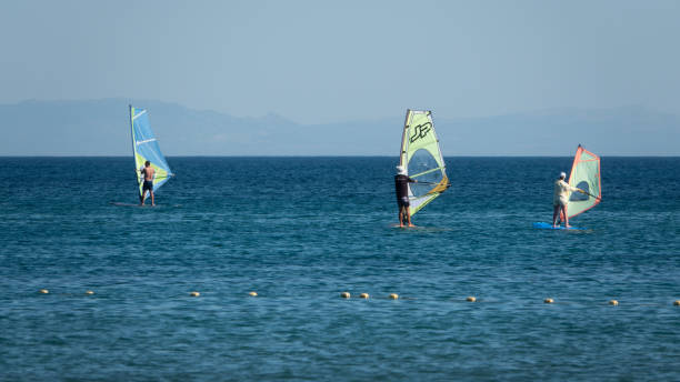 windsurfisti che si godono il mar egeo e il vento nella baia di gokceada kefalos contro il cielo limpido - clear sky water sports and fitness yacht foto e immagini stock