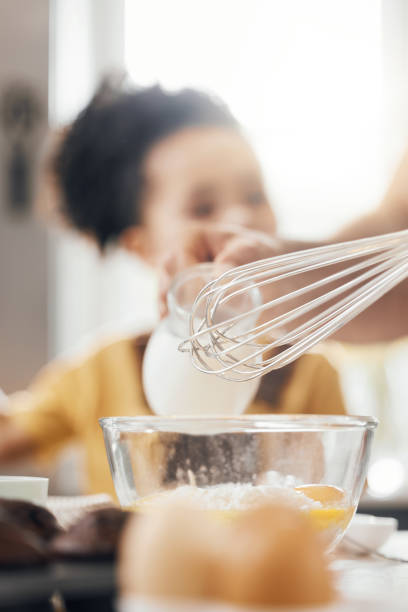 istock Whisk, egg and kitchen in closeup, kid and learning with muffins, cooking and helping hand from parents. Bowl, flour and child with development, teaching and baking with milk, cupcakes or family home 1673564831