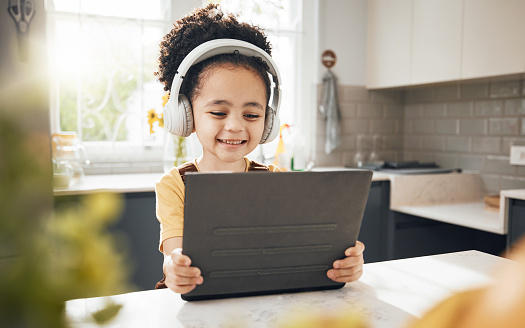 Tablet, headphones and child elearning in home, happy and online education for homeschool. Smile, technology and boy kid on video call, studying on internet and listening to music in virtual class