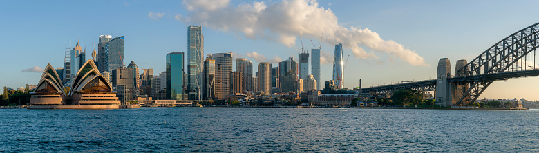 The spectacular cityscape of Sydney, Australia. Across the water we see the iconic form of the Sydney Opera House  and the towering skyscrapers of the CBD. Panoramic image.