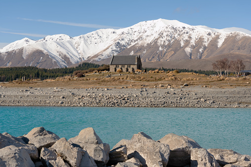 Winter sunlight falls upon the famous chapel on the shores of Lake Tekapo. In the background snow has fallen on the Southern Alps.