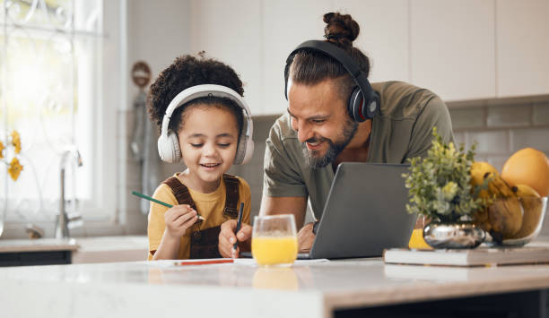 istock Elearning, dad and child in home with headphones, laptop and homework for online class. Computer, father and boy working together for virtual school, help with writing and kids education in kitchen. 1673578916