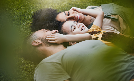 Care, happy and a family on the grass in nature for bonding, laughing and comfort. Love, smile and an interracial, father, mother and boy kid in a garden or backyard with an embrace together