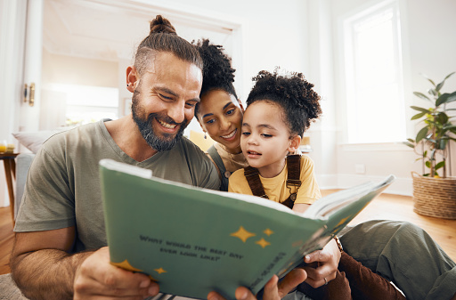Interracial parents, child and reading with book, story and learning with care, love and teaching on floor. Father, mom and kid with education, knowledge and listening for development in family home