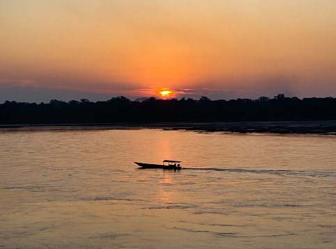Boat in the Madre de Dios River during the sunset in Puerto Maldonado, Peru Amazonas in South America.