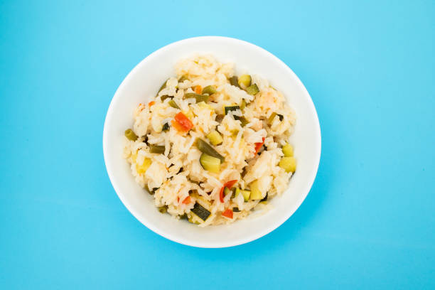 Cooked white rice mixed with colorful vegetables onion, green beans, tomato in white bowl