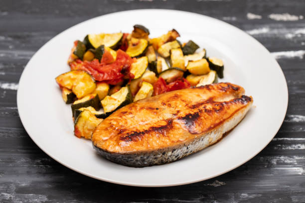 istock Fried salmon with vegetables on white plate 1673612823