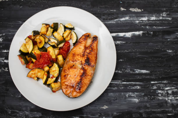 istock Fried salmon with vegetables on white plate 1673612971
