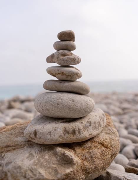 istock Tranquil beachside scene featuring a stack of rocks, with a quiet body of water in the background. 1673615505