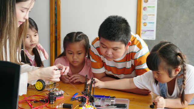 Joyful Asian School Kids Explore Robotics and Tech.