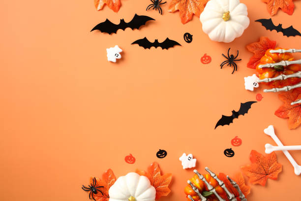 istock Halloween flat lay composition with pumpkins, bats, spider maple leaves on pastel orange background. Flat lay, top view, copy space. 1673663304